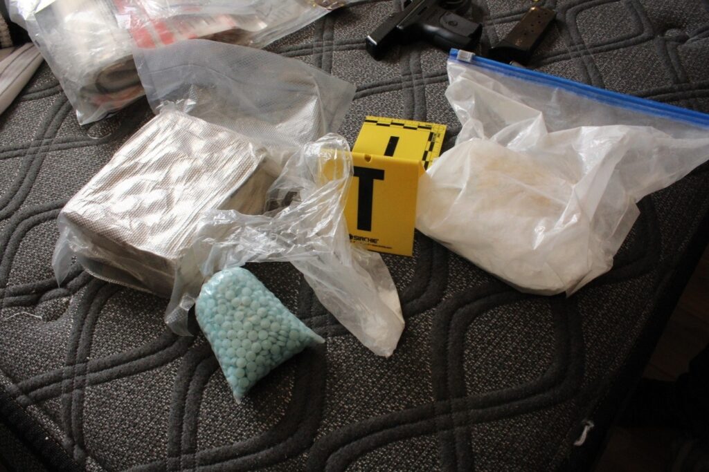 Bags of white substances, blue pills, and a handgun